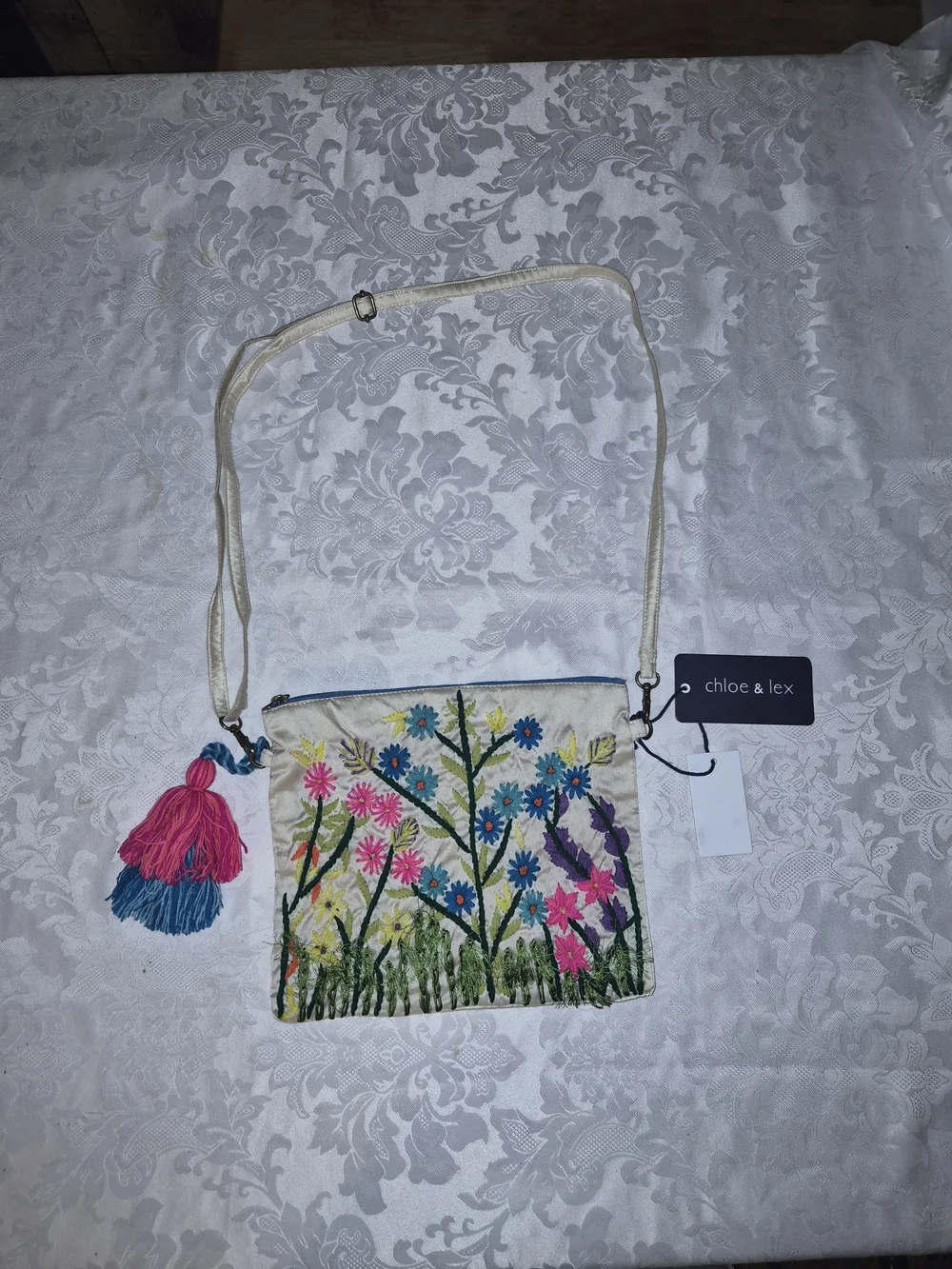 Chloe & Lex Cream Embroidered Floral Crossbody with Pink & Blue Tassel